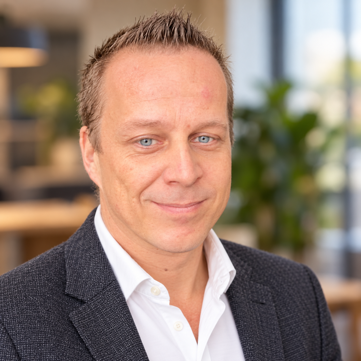 Stefan Willems in a charcoal blazer and white shirt with a softly blurred office background
